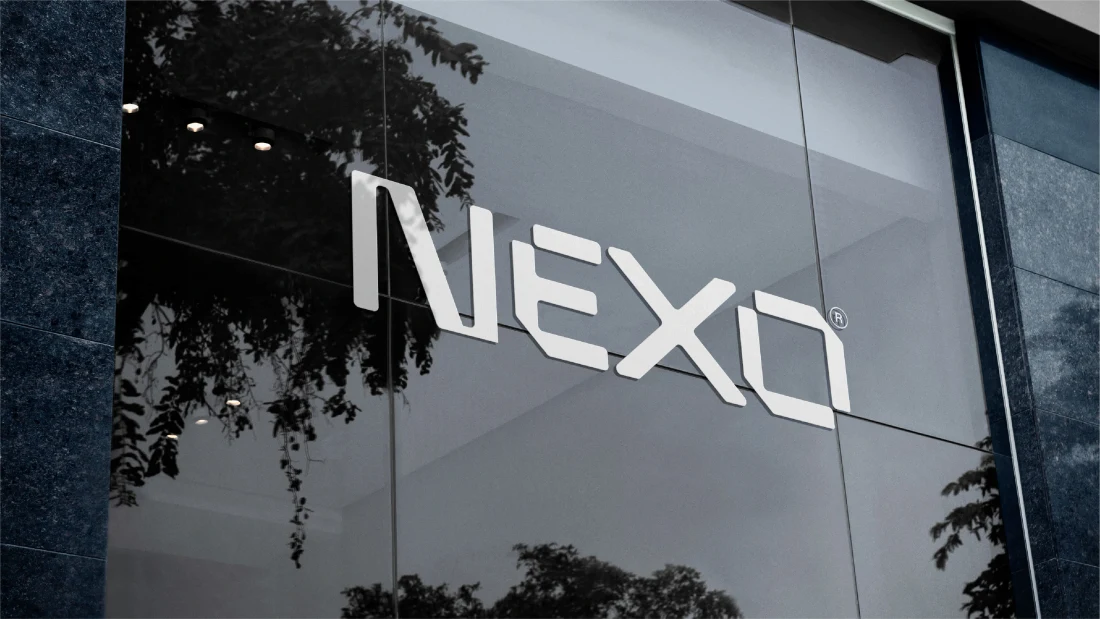 NEXO dimensional wordmark mounted on a contemporary glass building.