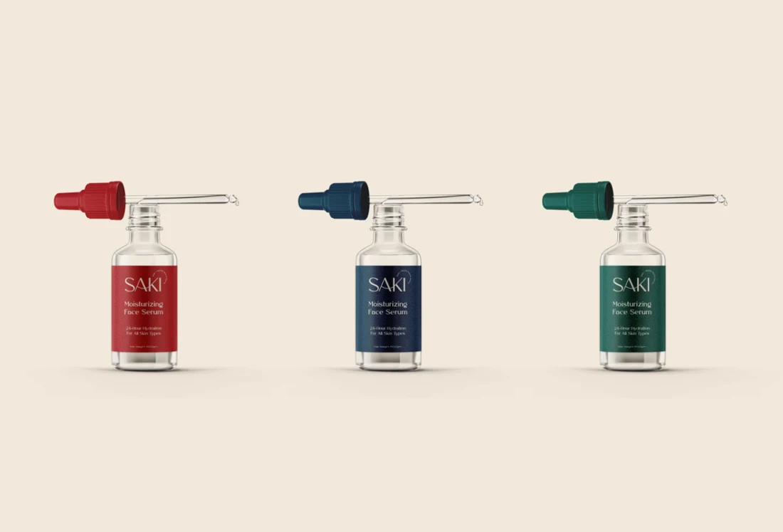 SAKI serum bottles with red, blue and green droppers on a cream surface.